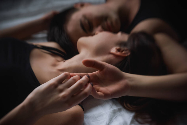 Defocused Top view of couple in love. Close-up portrait of the Lovers who lie on the bed at home, head to head. The morning of the newlyweds, tenderly resting on weekend at home. Concept of tactility - Foto, Imagem