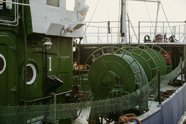 Detalle de los carretes de red de pesca verde en la cubierta del barco de pesca de amarre en el puerto de la ciudad polaca Gdansk - Foto, imagen