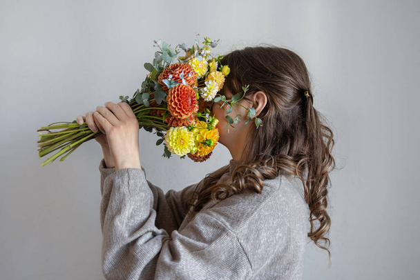 Young woman with a bouquet of fresh chrysanthemums on a gray background. - Foto, immagini