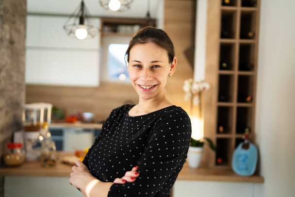 Waist up portrait of one adult caucasian woman beautiful millennial female standing in the kitchen at home copy space looking to the camera smiling happy confident real people - Foto, immagini