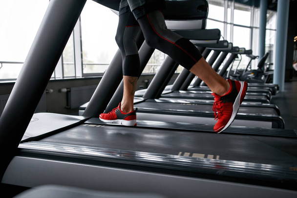 Closeup male legs in red trainers running on treadmill - Zdjęcie, obraz