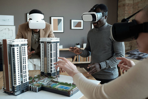 Group of architects in vr headsets standing around table with house layout - Photo, Image