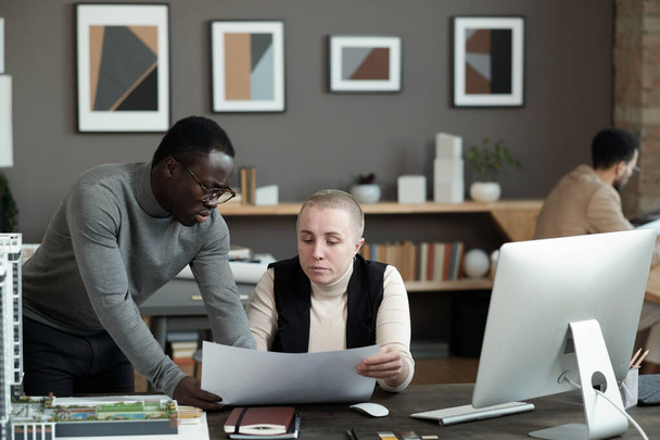 Zwei interkulturelle Männer und Frauen diskutieren Arbeitspapier - Foto, Bild
