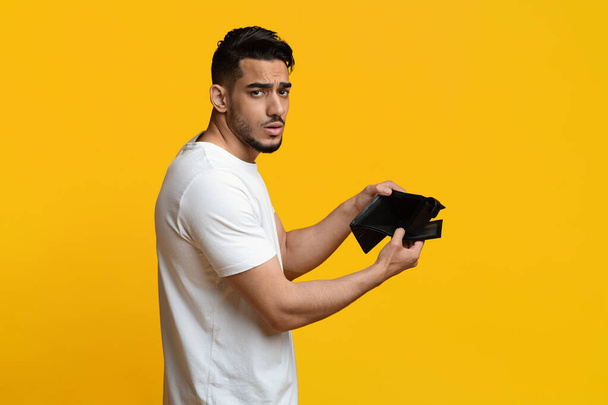 Ongelukkige Arabische man toont lege portemonnee in de studio - Foto, afbeelding