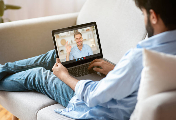 Man Videochatting met vriend terwijl ontspannen met laptop computer op de bank - Foto, afbeelding