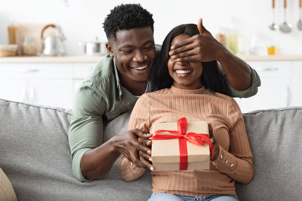 Loving african american guy making surprise for girlfriend, giving present - Foto, afbeelding