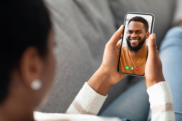 Nerozpoznatelná černá žena drží smartphone doma, dělat video hovor - Fotografie, Obrázek