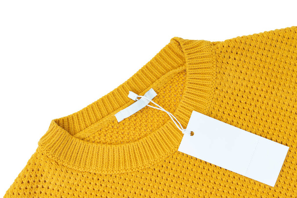 White blank rectangular clothing tag on yellow knitted sweater isolated on white background - Fotó, kép