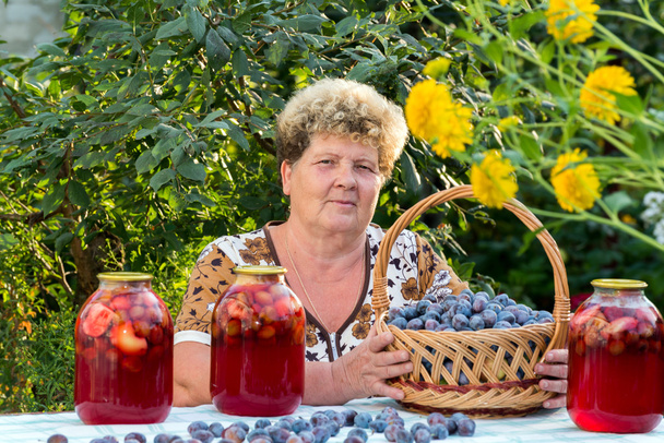 elderly woman with  jar of plum compote - Foto, afbeelding