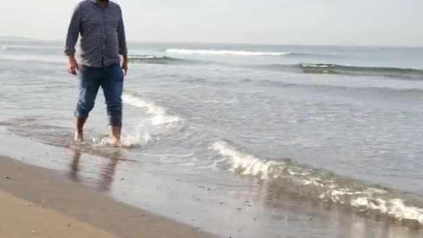 marchant par la mer, un homme d'âge moyen marche sur la plage en automne - Séquence, vidéo