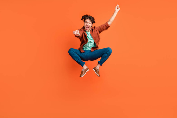 Full size photo of funky smiling screaming guy jump rodeo cowboy fooling around isolated on orange color background - Fotografie, Obrázek