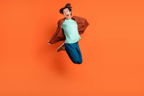 Full size photo of young handsome male jumping screaming fooling around carefree isolated on orange color background - Fotoğraf, Görsel