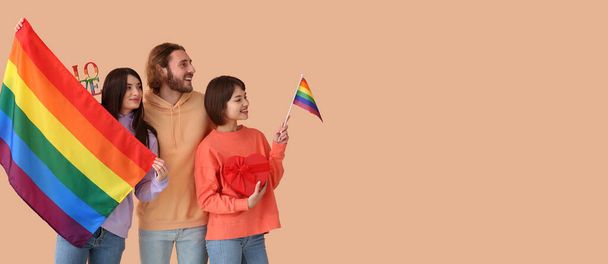 Mies ja kaksi kaunista naista sateenkaaren liput ja lahja värillinen tausta tilaa tekstiä. Polyamorin ja LGBT:n käsite - Valokuva, kuva