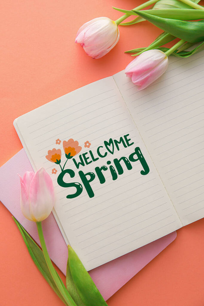 Zeszyt z tekstem WELCOME SPRING i kwiaty tulipan na różowym tle - Zdjęcie, obraz