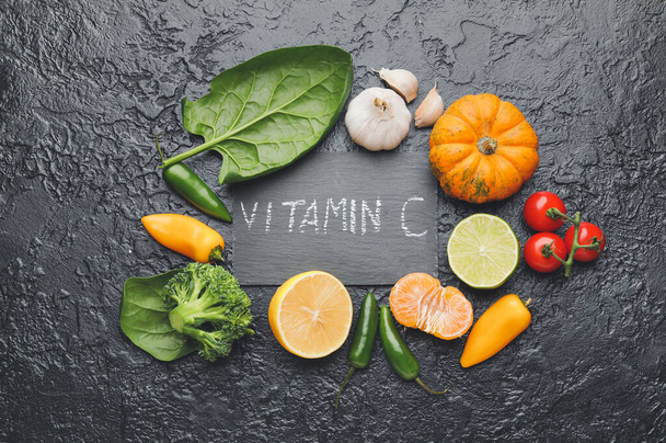 Text VITAMIN C and healthy products on dark background - Фото, изображение