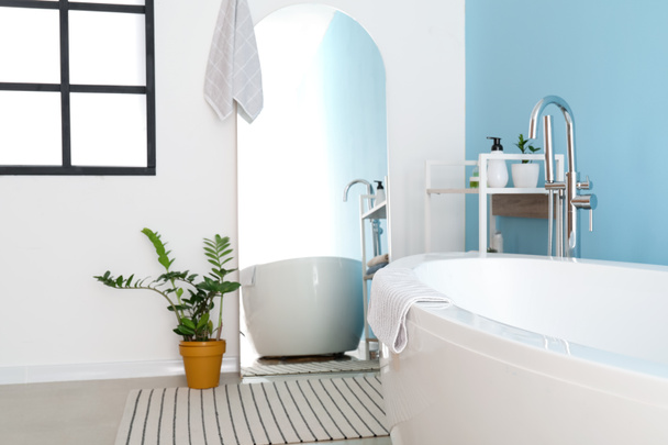 Elegante interior de baño moderno con espejo grande y planta de interior - Foto, imagen
