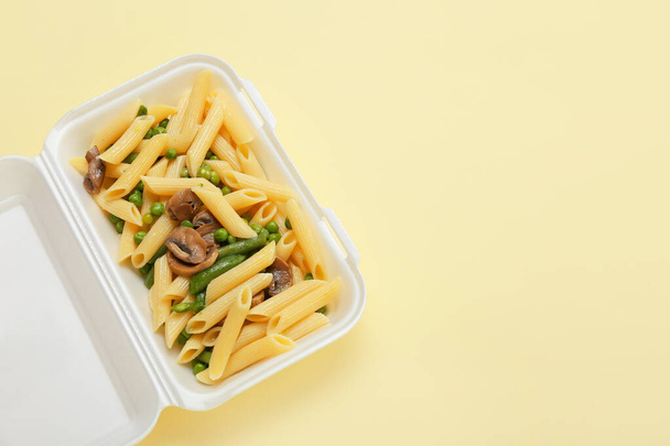 Delicious pasta with vegetables in container on color background - Photo, Image