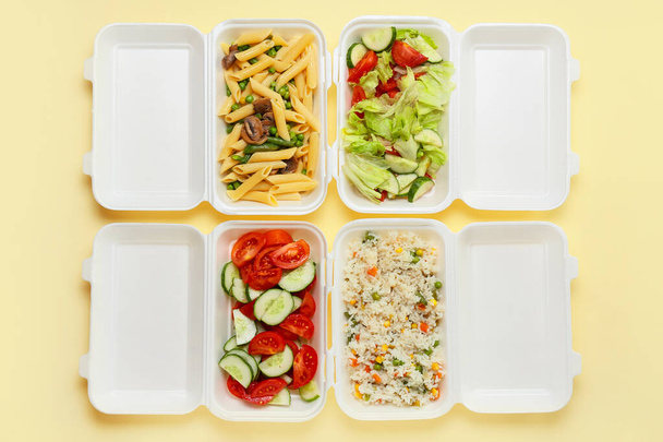 Food delivery containers with tasty meals on color background - Photo, Image