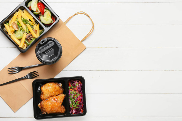Pudełka na lunch z jedzeniem, filiżanką, widelcami i papierową torbą na białym drewnianym tle - Zdjęcie, obraz