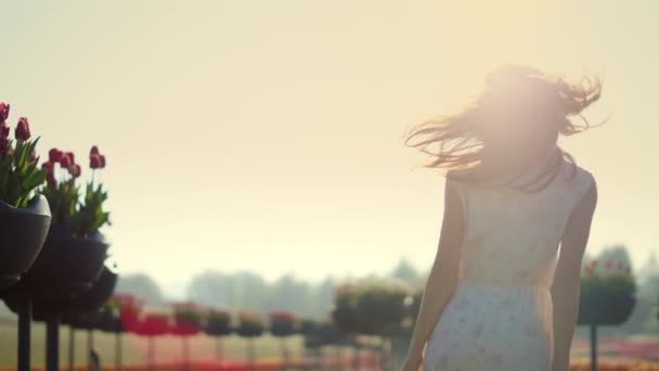 Mujer sonriente caminando en el jardín. Chica emocional tocando el cabello en la reflexión del sol. - Metraje, vídeo