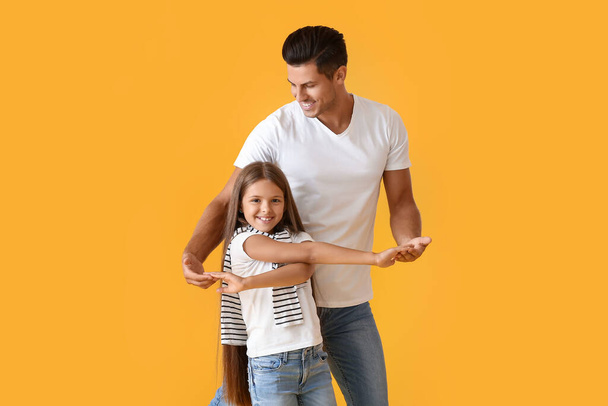 Счастливый танцующий мужчина и его дочь на цветном фоне - Фото, изображение