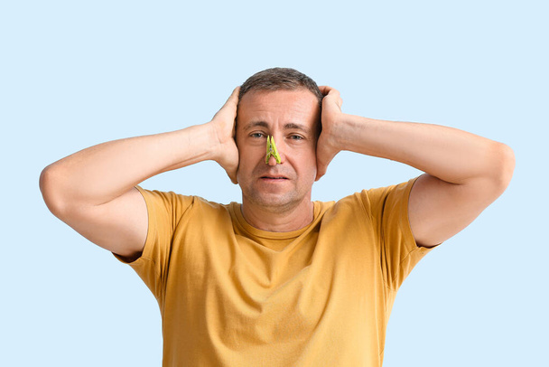 Stres nemocný zralý muž s kolíkem na nose proti barvě pozadí - Fotografie, Obrázek