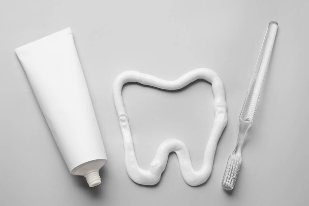 Tube, Zahnbürste und Zahn mit Zahnpasta auf grauem Hintergrund gezeichnet - Foto, Bild