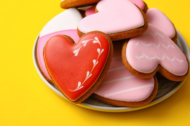 Assiette avec de savoureux biscuits en forme de coeur sur fond jaune, gros plan - Photo, image