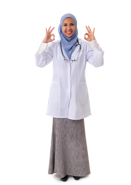 medicine, healthcare, charity and people concept - full size portrait of smiling muslim female doctor wearing white coat and showing ok sign with two arms, isolated over white background - Photo, image