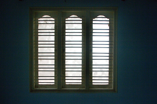Дерев'яна віконна рамка з захисними смугами та скляними панелями, вид зсередини кімнати
 - Фото, зображення