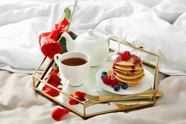 Tray with tasty breakfast and rose flower for Valentine's Day on bed - Фото, изображение