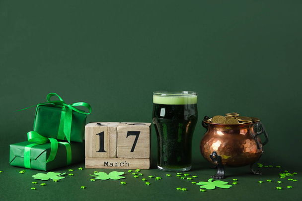 Maceta con monedas, vaso de cerveza, calendario y cajas de regalo sobre fondo verde. Celebración del Día de San Patricio - Foto, Imagen