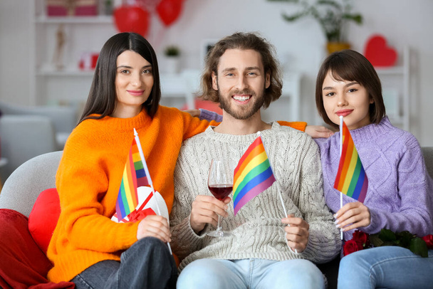 Άντρας και δύο όμορφες γυναίκες γιορτάζουν την ημέρα του Αγίου Βαλεντίνου στο σπίτι. Έννοια της πολυγαμίας και ΛΟΑΤ - Φωτογραφία, εικόνα