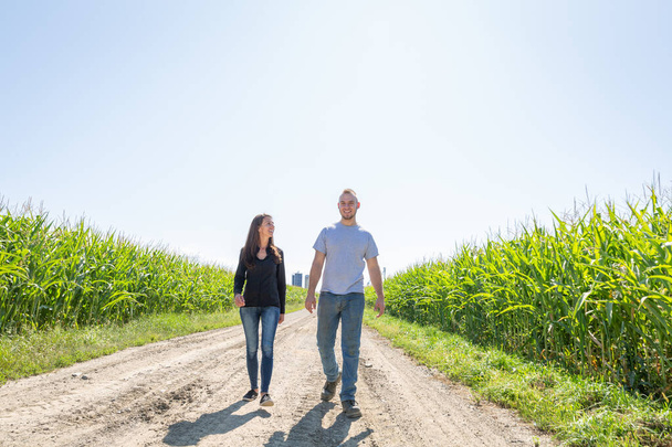 Una coppia di imprenditori agricoli che camminano in una fattoria in un campo di mais - Foto, immagini