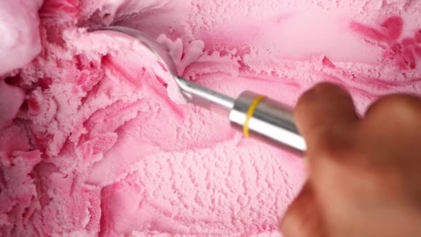 Mano de cámara lenta sosteniendo una cuchara para recoger helado de fresa. Patrón y textura de helado suave. Concepto alimenticio. - Imágenes, Vídeo