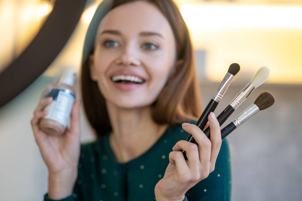 Young woman holding face brushes and smiling - Photo, Image