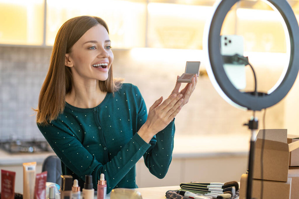 Young smiling woman shpowing new eyeshadows to onine audience - Foto, Bild