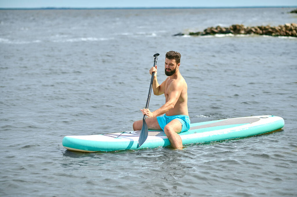 A dark-haired young man on a kayak - Foto, afbeelding