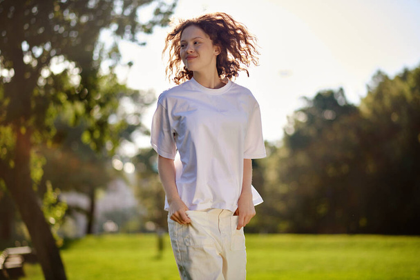 Wavy-haired girl enjoying a sunny morning in the park - Foto, afbeelding