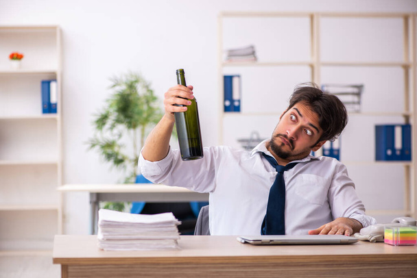 Young alcohol addicted employee sitting in the office - Foto, Bild