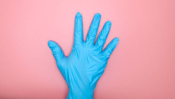 Doctor hand in Medical gloves blue on pink background, Top view Blank for design copy space - Fotoğraf, Görsel