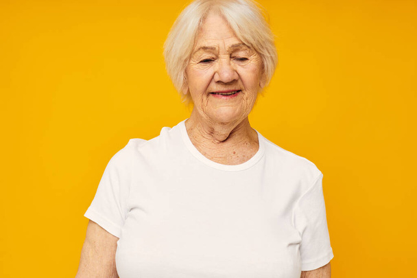 ältere Frau im weißen T-Shirt posiert lustig isoliert Hintergrund - Foto, Bild