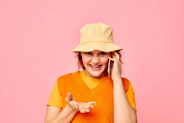 portrait of a young woman communicates on the phone in yellow hat fashion cropped view unaltered - Фото, изображение