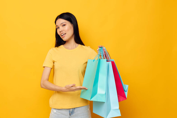 woman in a yellow T-shirt with multicolored shopping bags isolated background unaltered - Фото, изображение