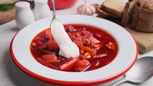 Eating beetroot soup borsch with sour cream, dill and bread with spoon. Russian or Ukrainian cuisine concept. - Video