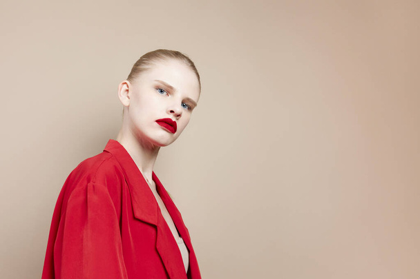 portrét ženy červené rty módní bunda béžové pozadí - Fotografie, Obrázek