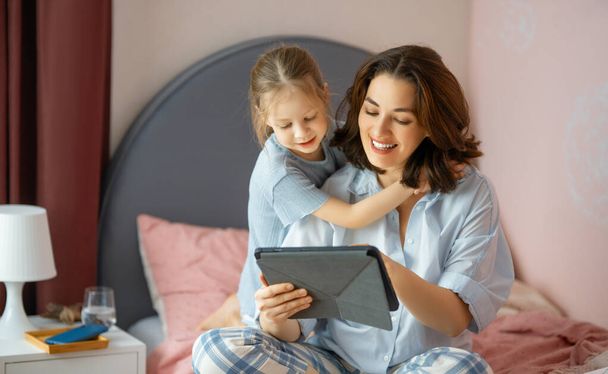 Happy loving family. Young mother and daughter girl using tablet pc. Funny mom and lovely child are having fun at home. - Foto, Bild