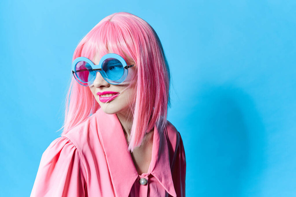 glamoureuze vrouw in blauwe bril draagt een roze pruik studio model ongewijzigd - Foto, afbeelding