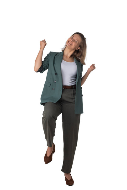 Happy smart business woman in suit smiling, holding hands in the air and celebrating, walking isolated on white background in studio - Valokuva, kuva