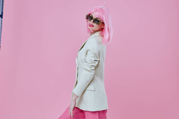 Hermosa chica de moda con gafas de sol pelo rosa posando fondo de color inalterado - Foto, imagen